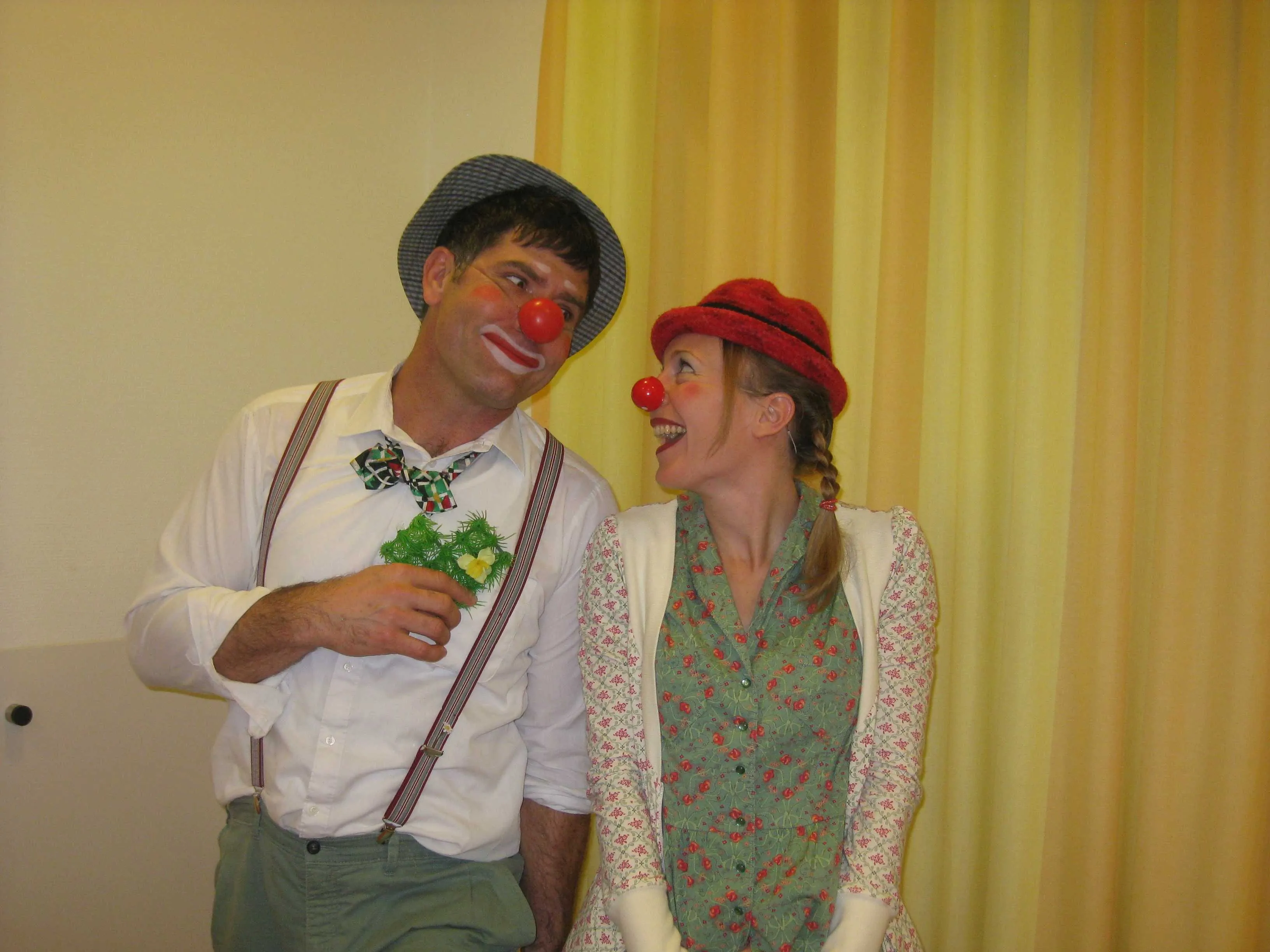 Clown Dodo und Clownin Pepa vor einem gelben Vorhang